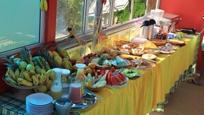 Uma mesa de buffet com diversas frutas, legumes e bebidas.
