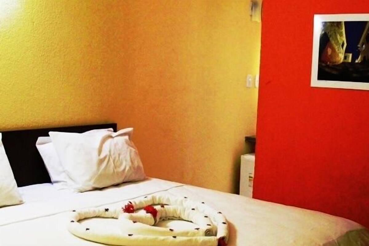 Una habitación de hotel con una cama, almohadas y una pared roja.