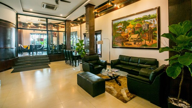 A spacious lobby with a high ceiling, a large painting, and a seating area with leather sofas and a coffee table. - Seasons Riverside Hotel (Vientiane)