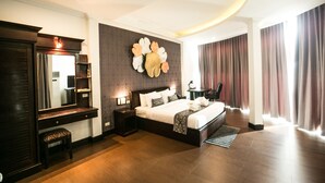 A modern hotel room with a large bed, a desk, a chair, and a wall-mounted artwork. - Seasons Riverside Hotel (Vientiane)