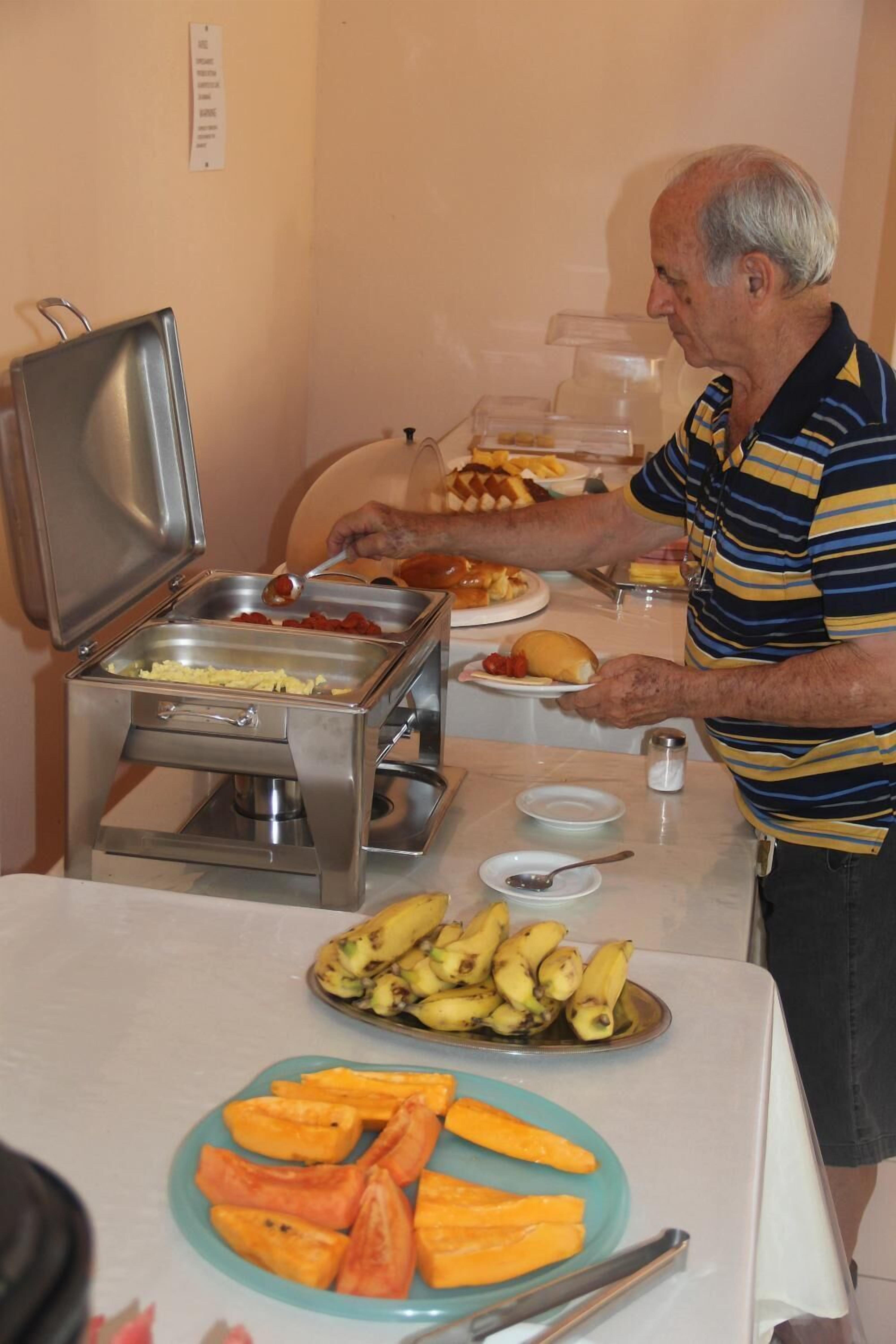 A buffet setup with various food items and a person serving.