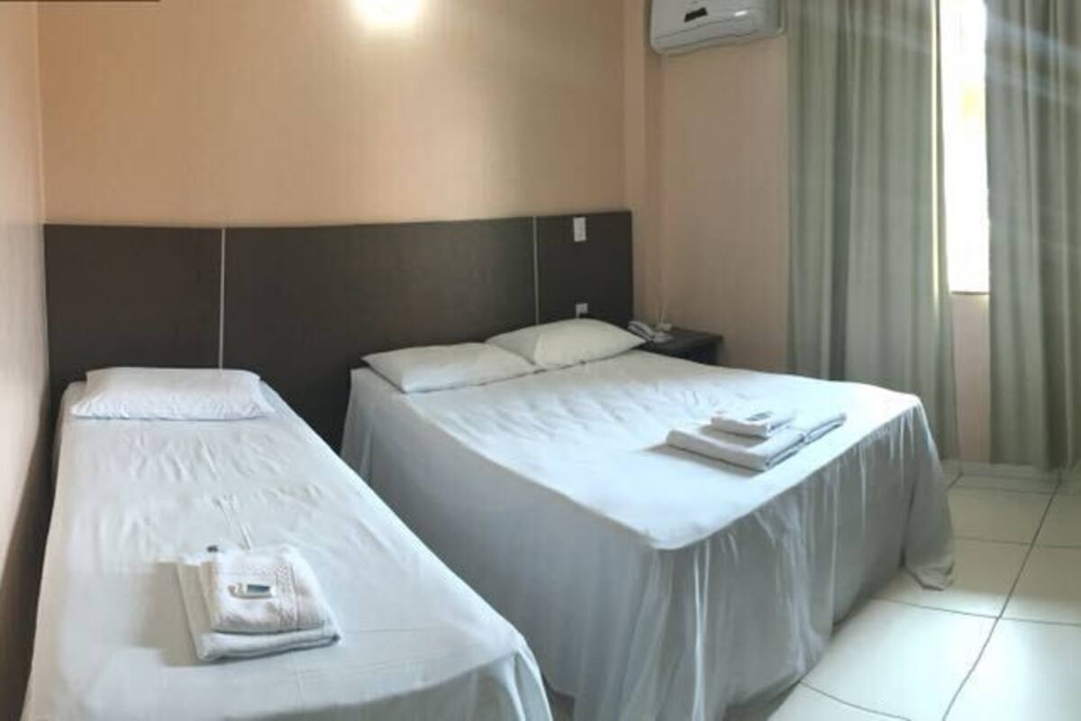 Habitación de hotel con dos camas, televisión y un escritorio pequeño.