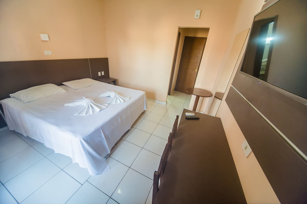 Una habitación de hotel con cama, escritorio y televisión.