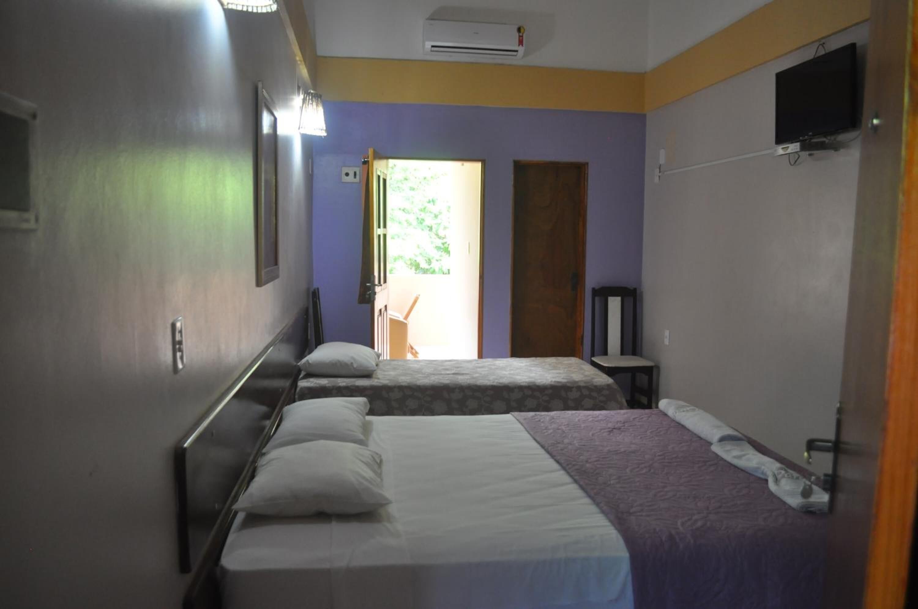 Een hotelkamer met twee bedden, een televisie en een airconditioning.