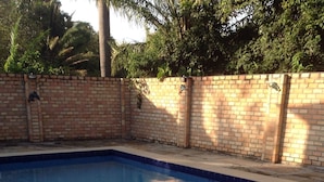 Piscina com muro de tijolos e deck revestido com azulejos.