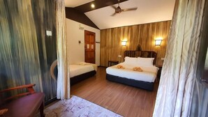 Une chambre d’hôtel avec deux lits, un plancher en bois, un ventilateur de plafond et une porte en bois.