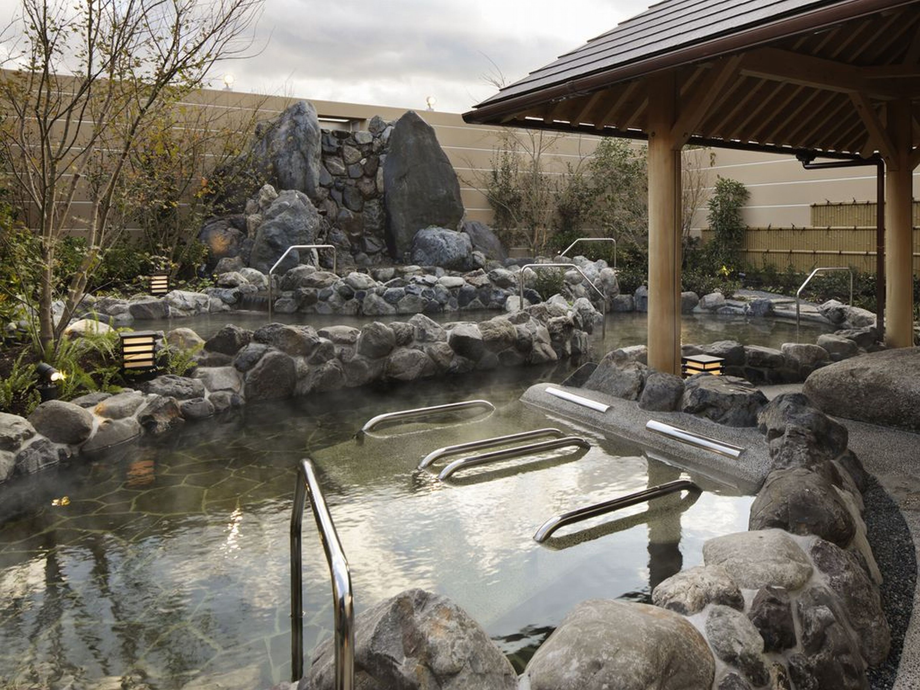 A hot spring area with stone steps and a wooden pavilion.