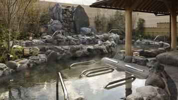 A hot spring area with stone steps and a wooden pavilion.