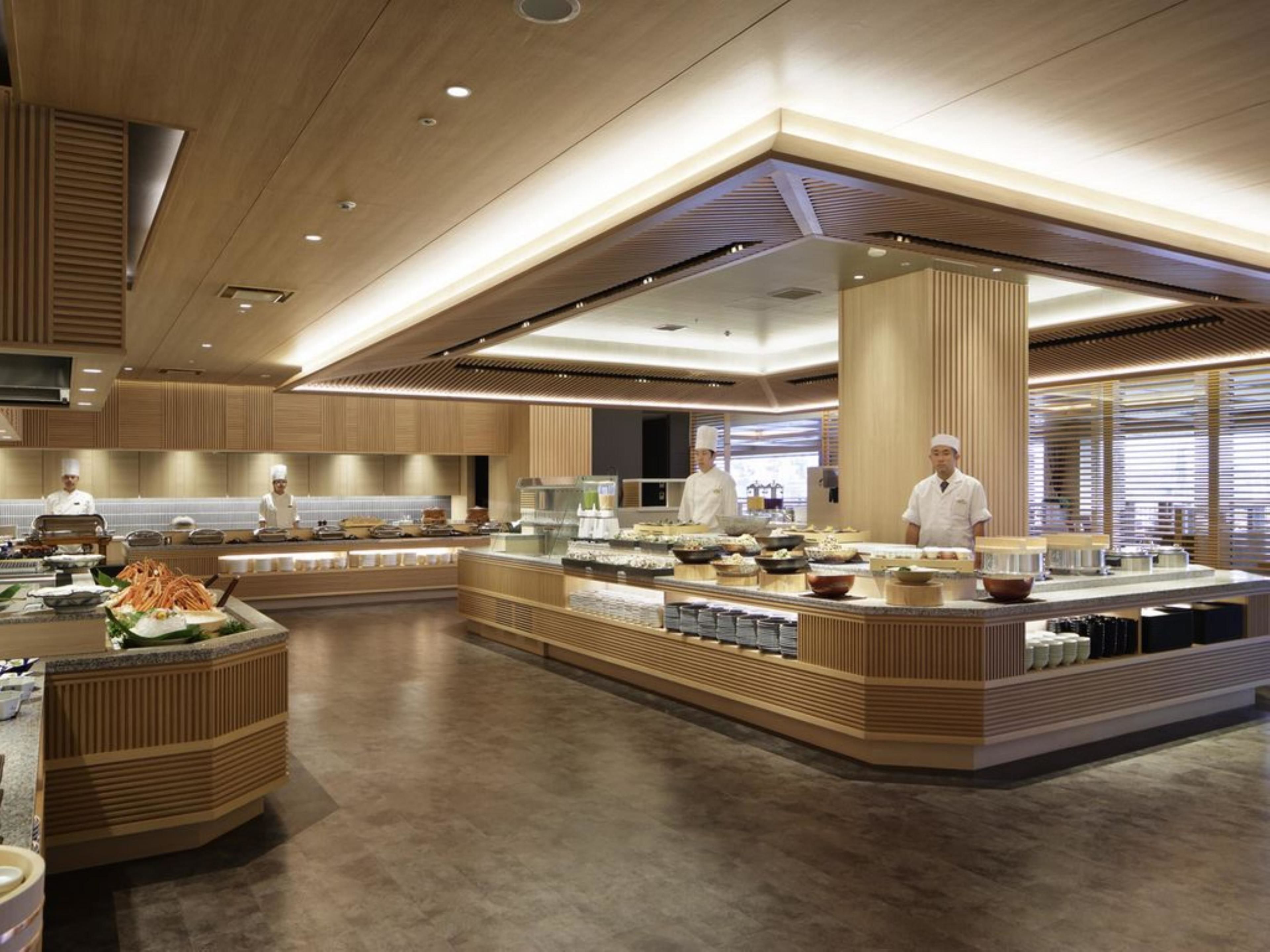 A modern kitchen with chefs preparing food, wooden paneling, and a central island with various dishes.