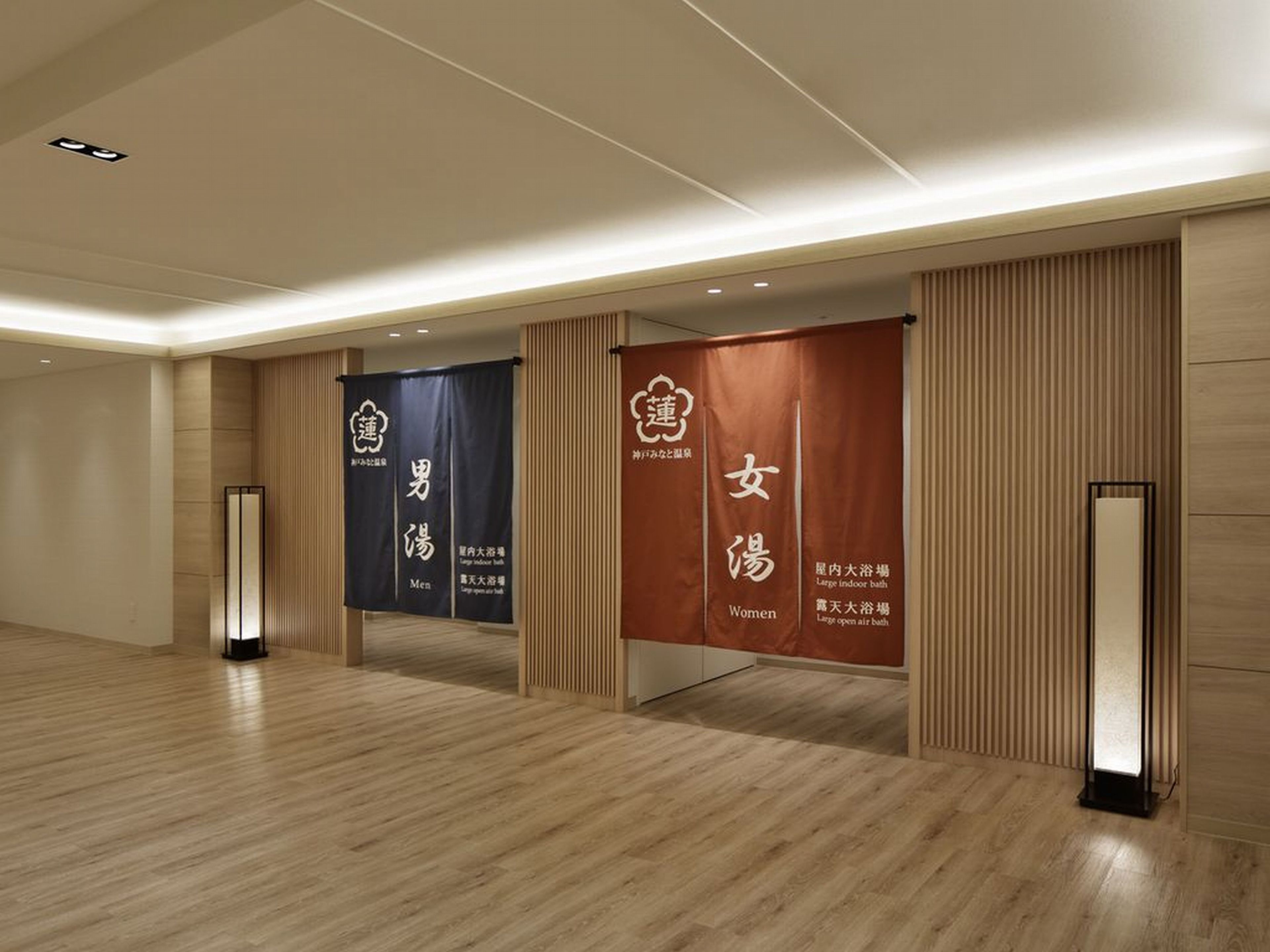 A spacious hallway with wooden flooring and two banners advertising large indoor baths for men and women.