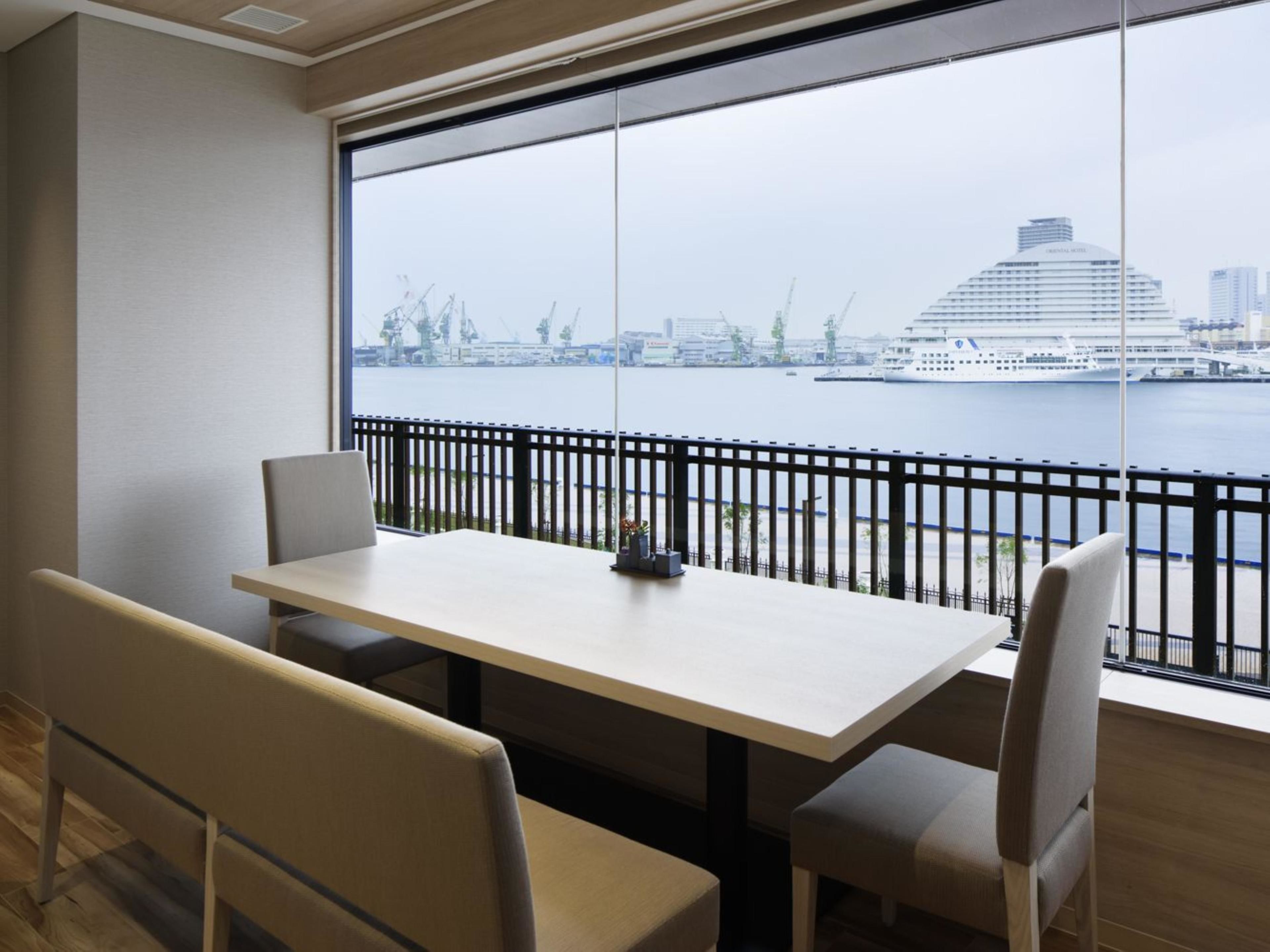 Una habitación moderna con un ventanal amplio que ofrece vistas de un río y edificios lejanos.