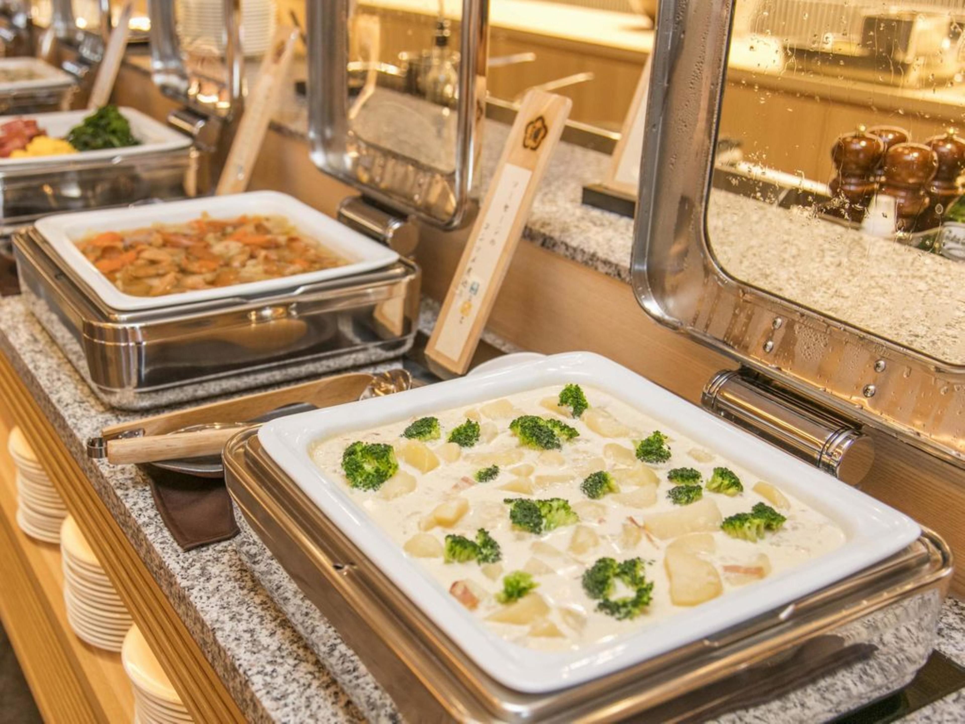 Ein reichhaltiges Buffet mit verschiedenen Gerichten, darunter eine cremige Suppe mit Brokkoli und Kartoffeln.