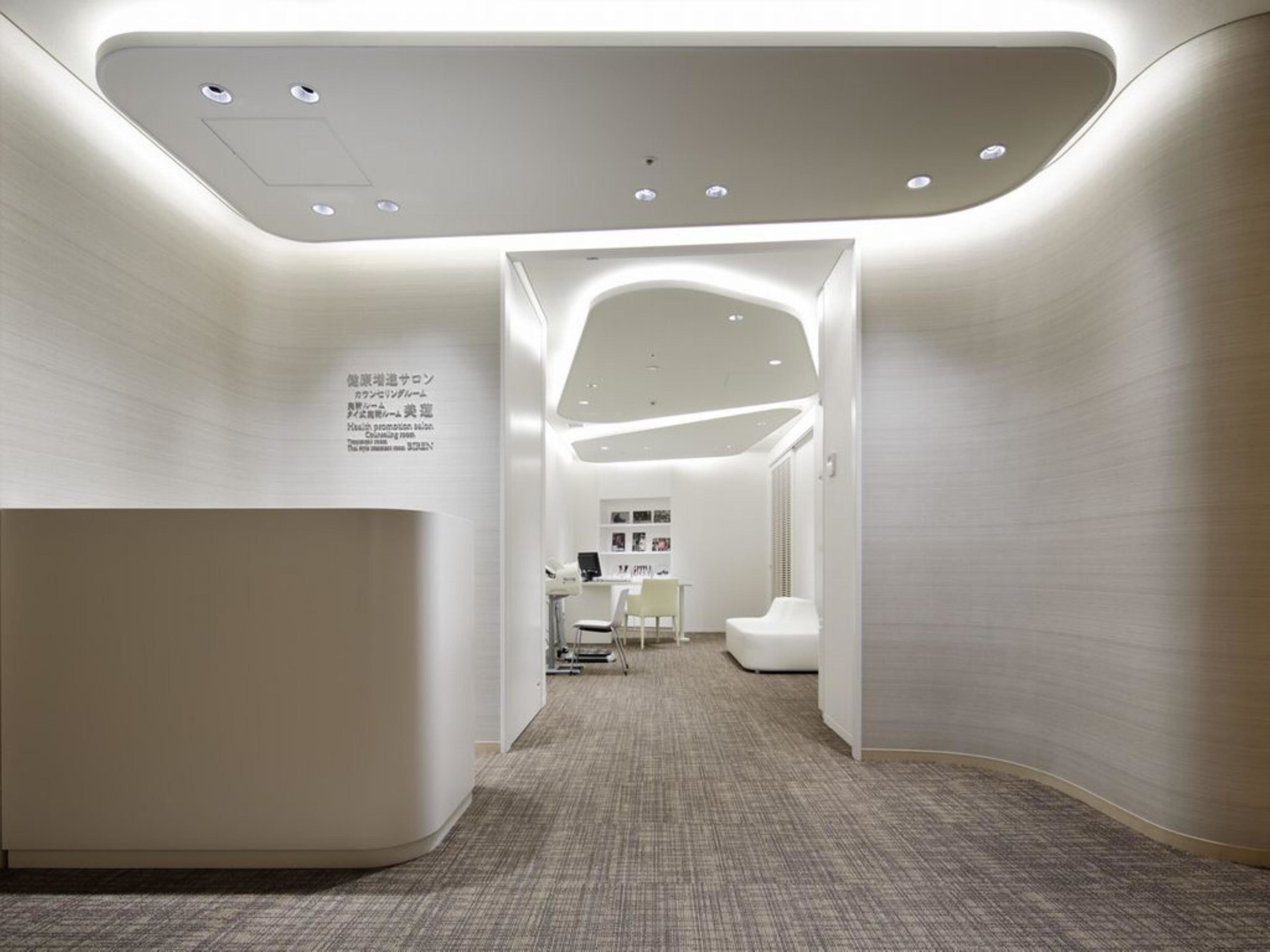 Un área de recepción moderna con una pared curva, un mostrador de recepción y un espacio de estar.