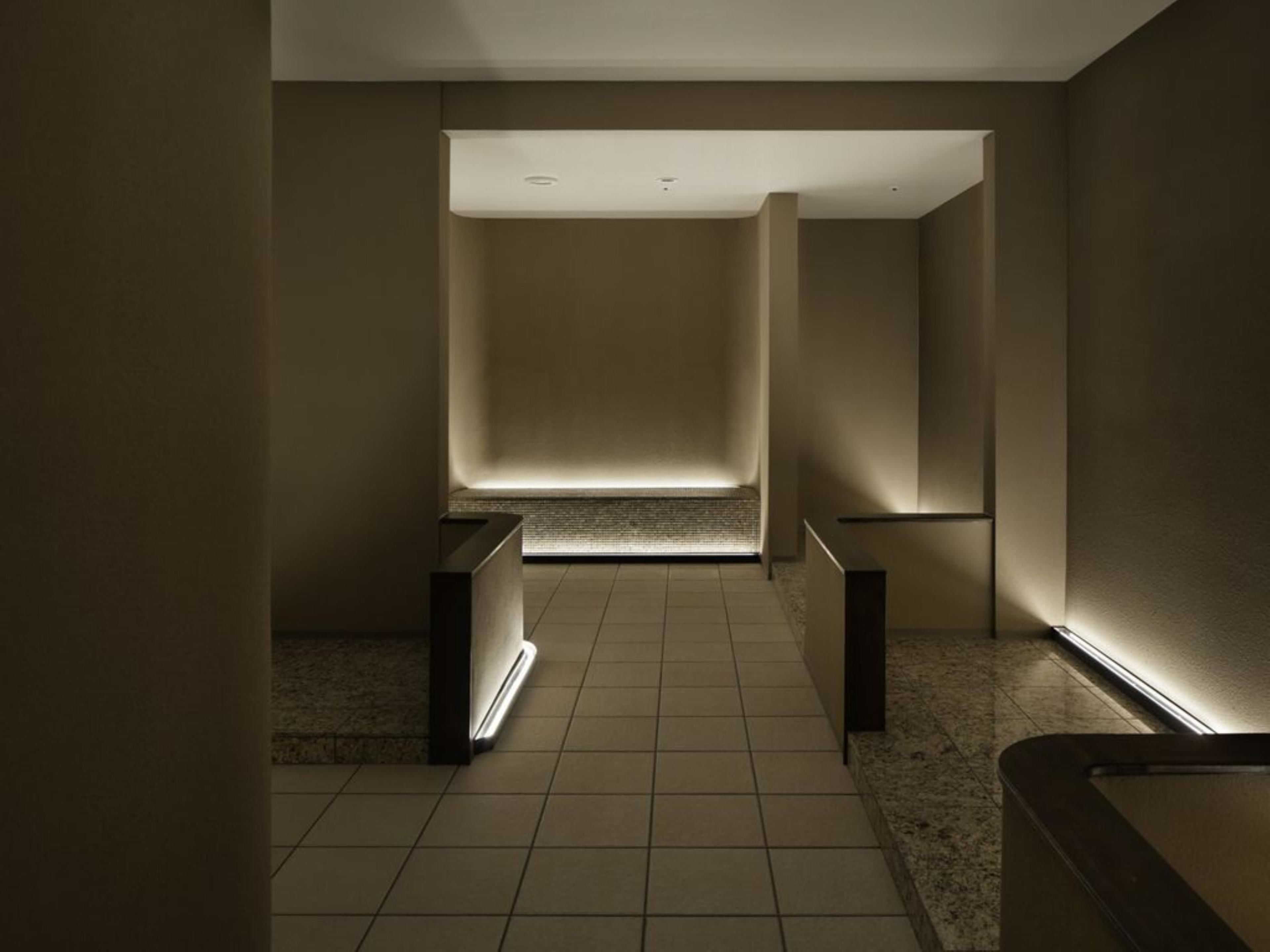 Un bany modern i minimalista amb sòl de rajola, una panca central i un sostre inclinat.