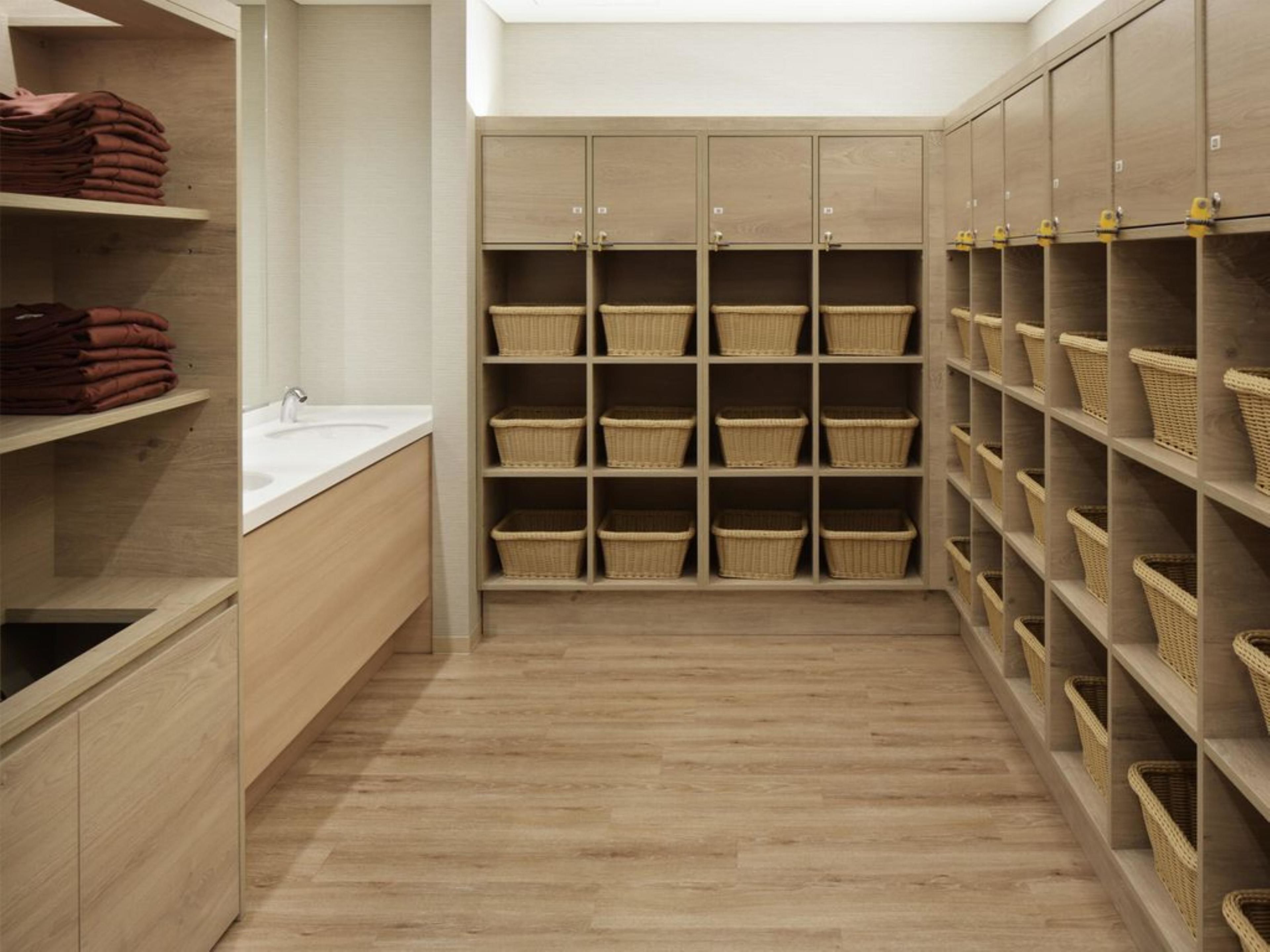 Un baño moderno con armarios de madera, un lavabo y cestos de mimbre para guardar objetos.