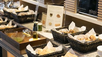 Montaje de bufé con diferentes alimentos en cestas, un dispensador de bebidas y un microondas.