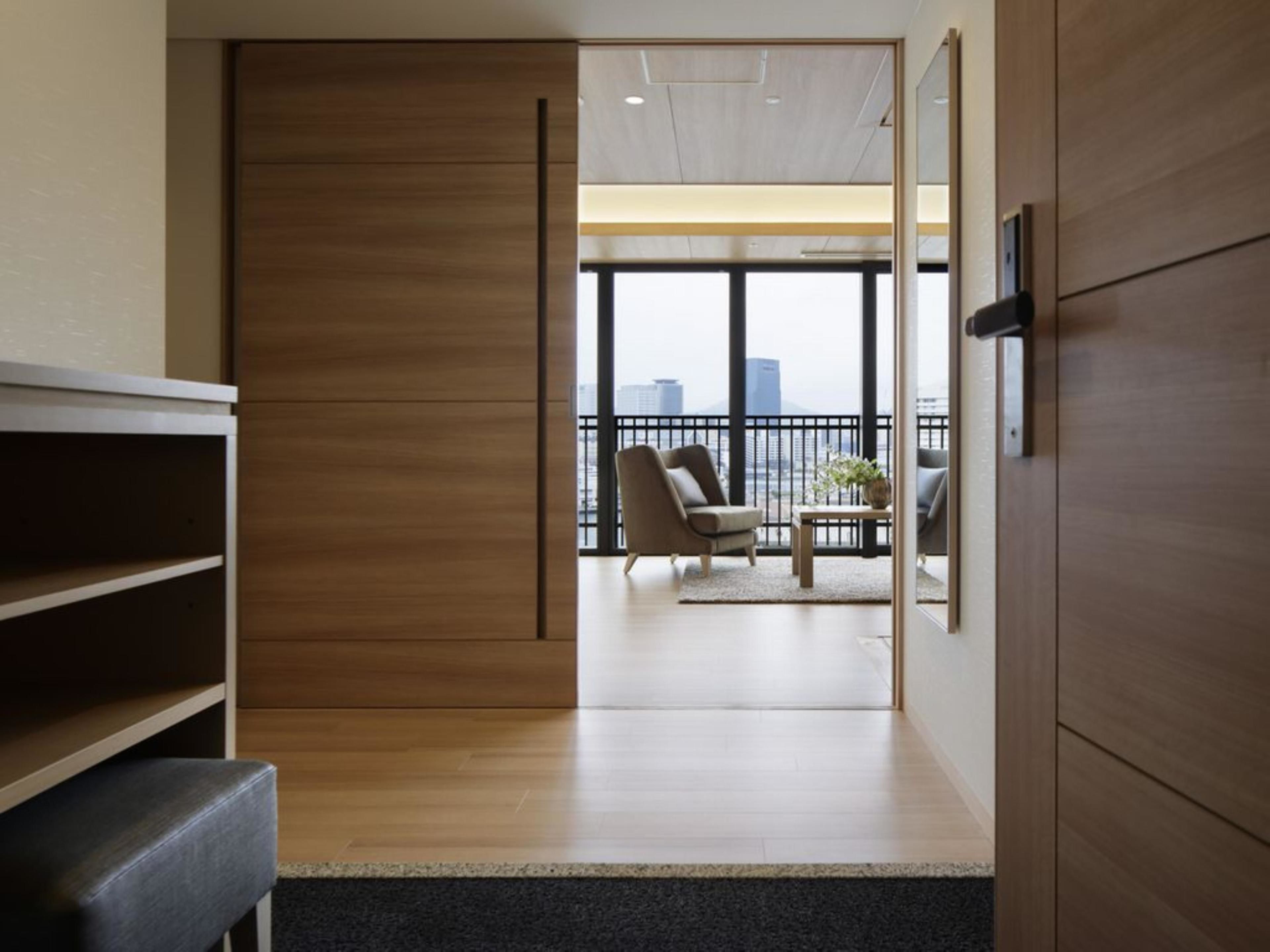 Ein modernes Interieur mit Holzboden, einer Couch und Blick auf die Stadt durch große Fenster.