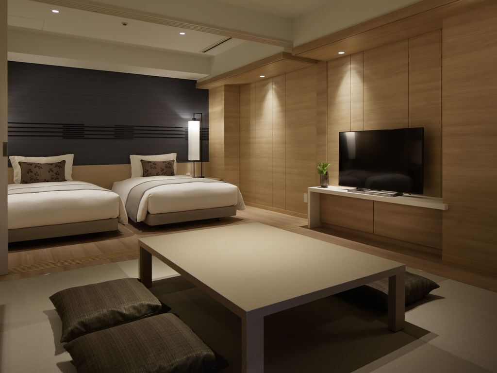 Une chambre d’hôtel moderne avec deux lits, un téléviseur à écran plat, une table basse et un mur décoratif en bois.