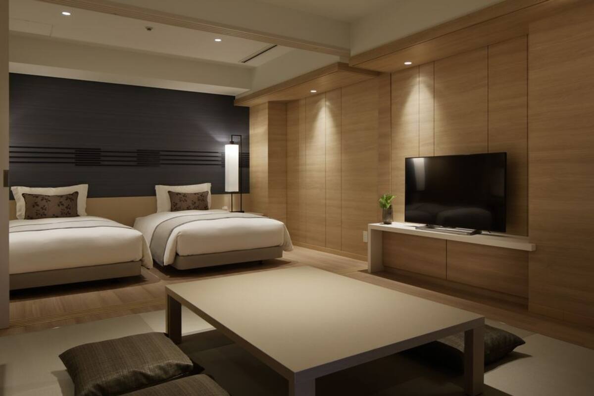 Een moderne hotelkamer met twee bedden, een flatscreen televisie, een salontafel en een houten accentmuur.
