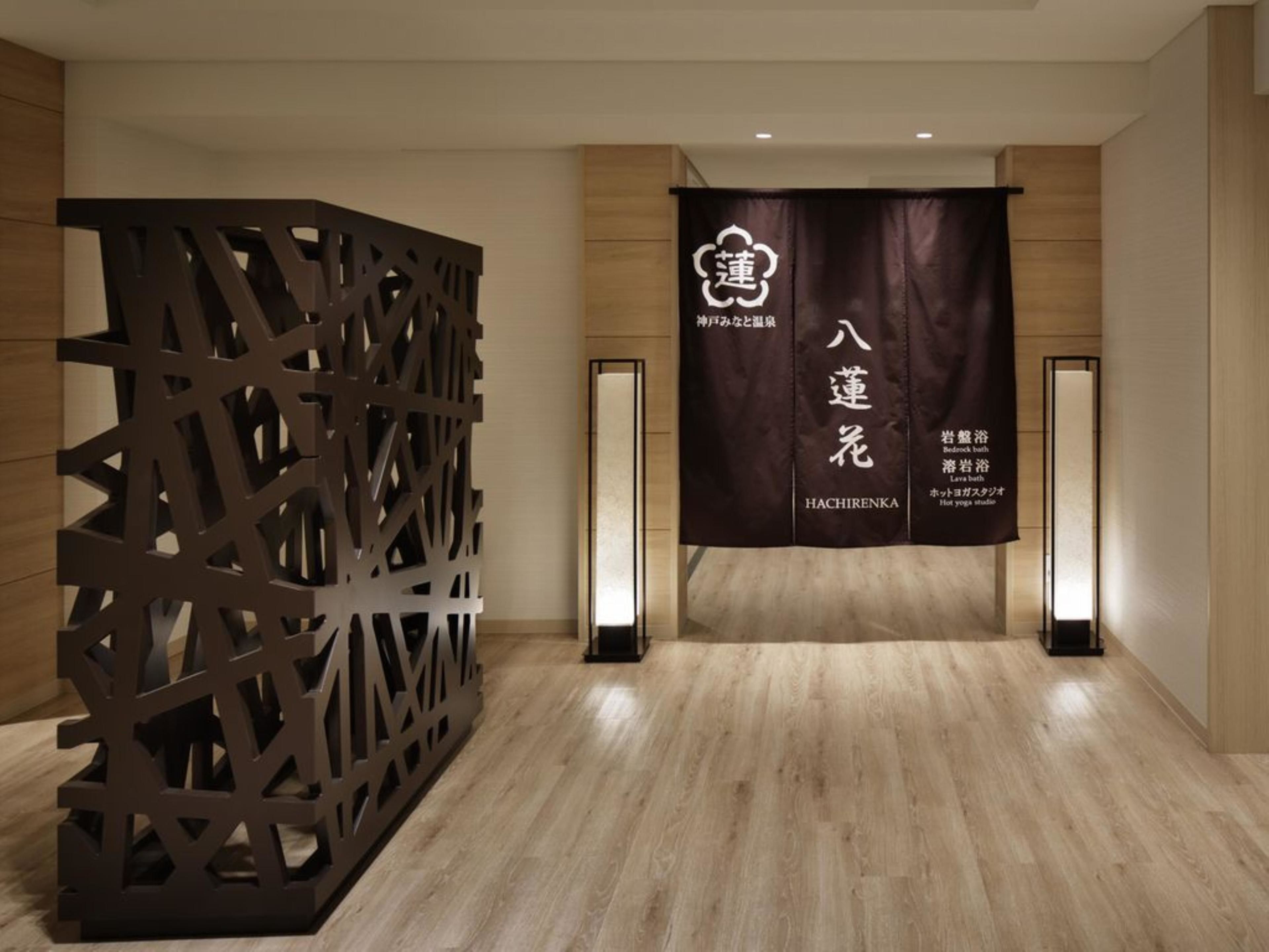 A hotel lobby with a wooden floor, a decorative wall, and a banner with Japanese text.