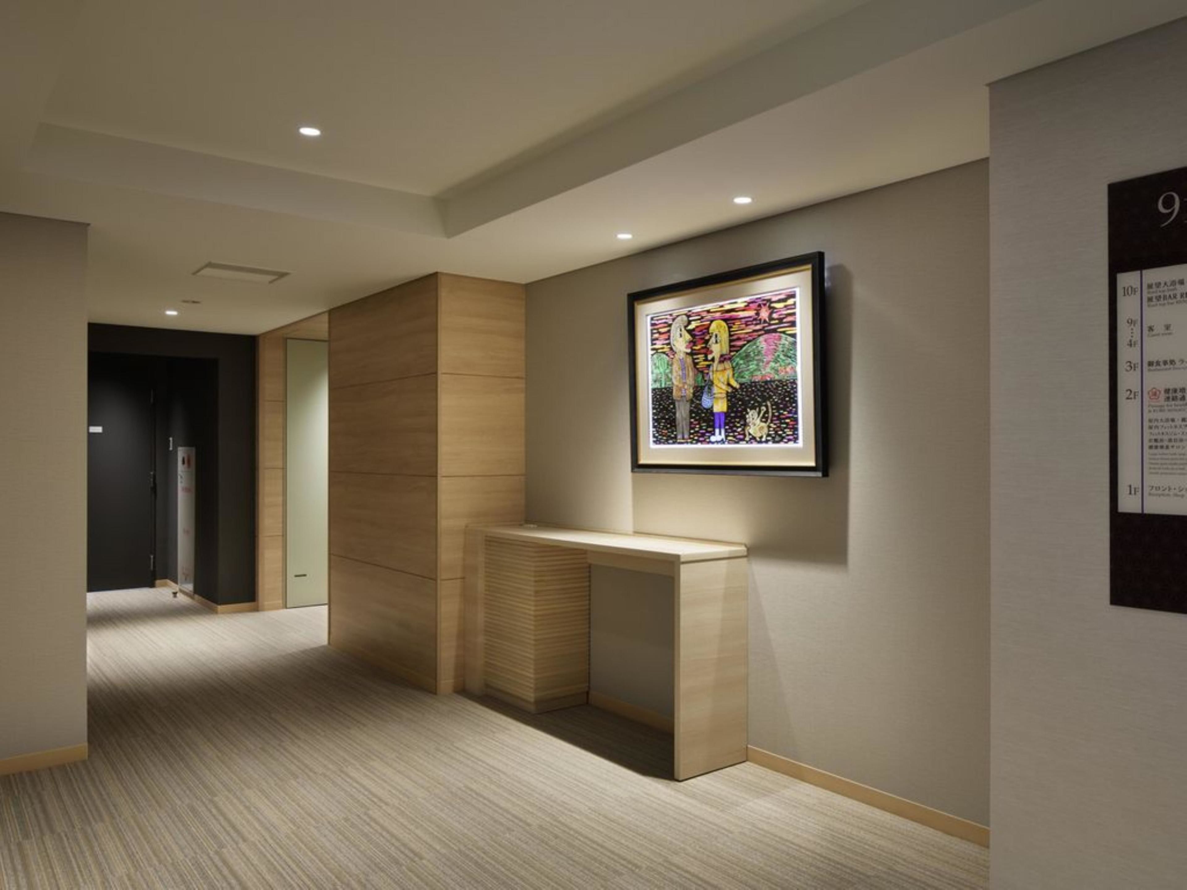 A hallway with a wooden desk and a framed artwork on the wall.