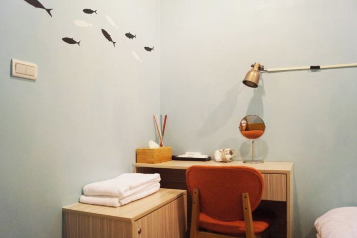 A room with a desk, chair, and a wall decal of fish.