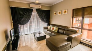 A modern living room with a leather sofa, a glass coffee table, and a flat-screen TV. - Marina Travellers Suite Marina Court (Kota Kinabalu)