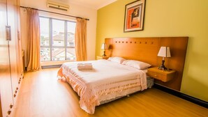 A hotel room with a large bed, two bedside tables with lamps, a window with curtains, and a framed picture on the wall. - Marina Travellers Suite Marina Court (Kota Kinabalu)