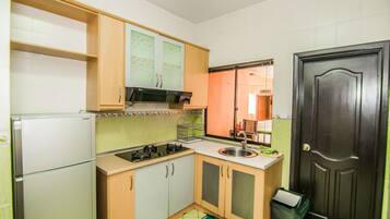 Cocina compacta con refrigerador, estufa, pileta y alacenas.