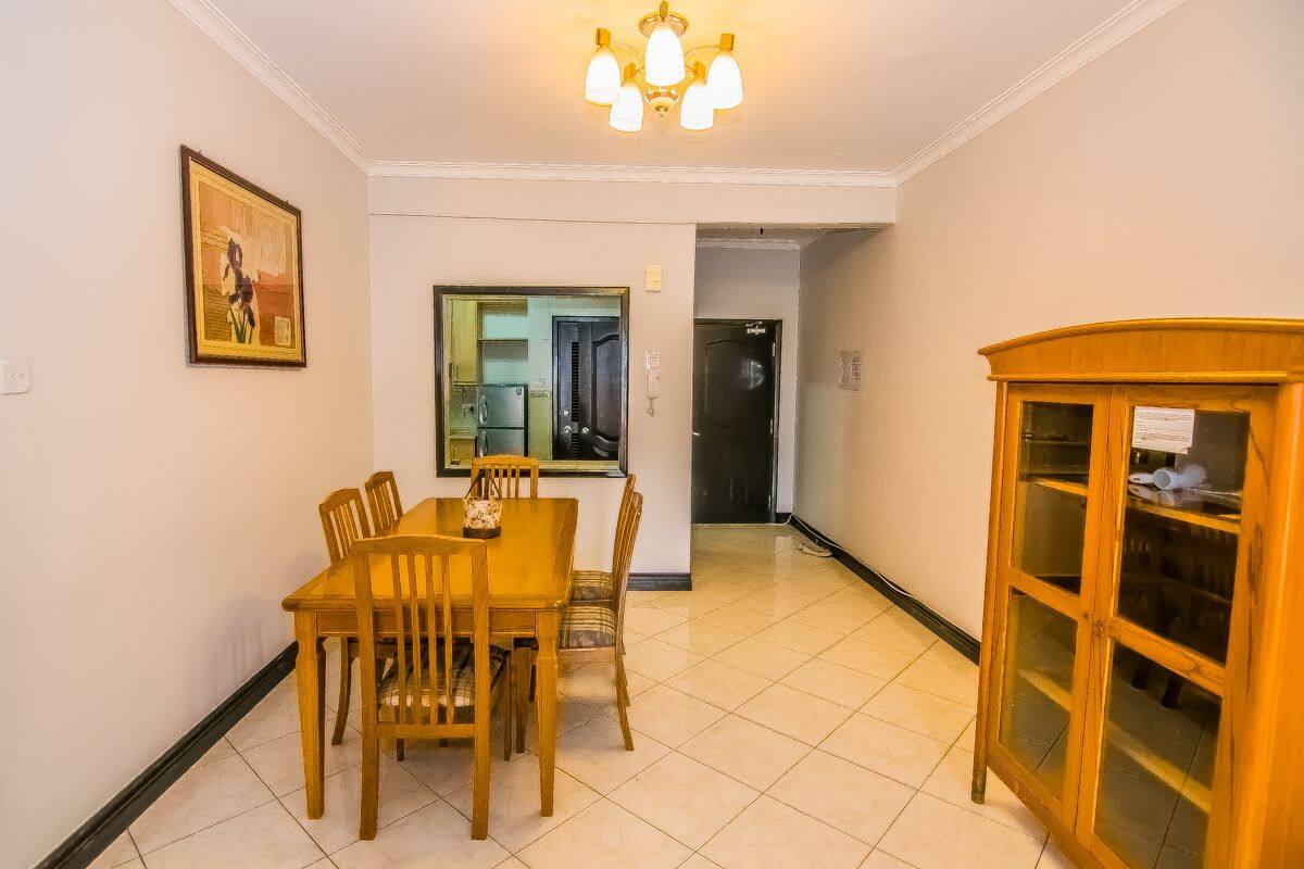 A dining area with a wooden table and chairs, a cabinet with glass doors, and a framed picture on the wall.