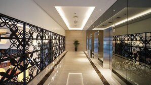 A modern hallway with a geometric metal railing, a central light fixture, and a potted plant. - The Margo Hotel (Depok)