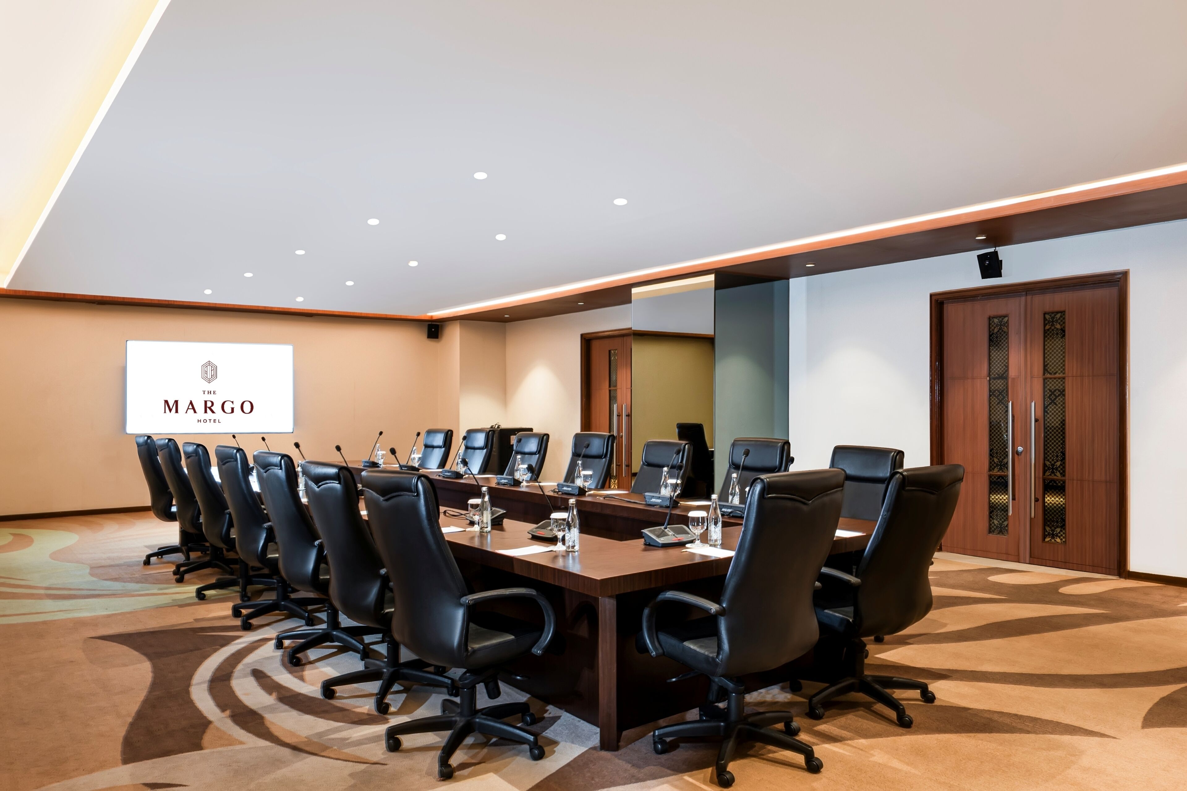 Un salón de conferencias con una larga mesa, varias sillas y un logotipo en la pared.