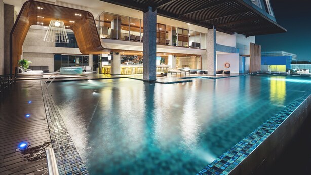 Un hotel moderno con una amplia piscina interior, zona de bar y un área de descanso.