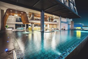 A modern hotel with a large indoor pool, a bar area, and a seating lounge. - The Margo Hotel (Depok)