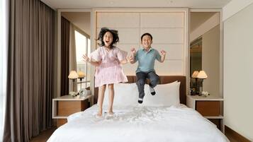 A hotel room with a bed, nightstands, lamps, and a large window with curtains.