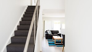 A modern staircase with a metal railing, leading to a living area with a sofa and a coffee table.