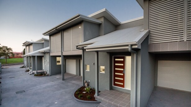 A modern building with a series of connected units, each featuring a front door and a small porch area.