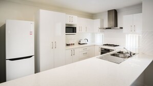 A modern kitchen with white cabinetry, a stainless steel sink, and a built-in microwave.