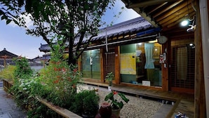 A traditional Japanese building with wooden architecture, a wooden deck, and potted plants.