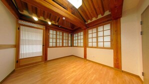A room with wooden flooring, traditional sliding doors with glass panels, and a sloped ceiling with exposed beams.