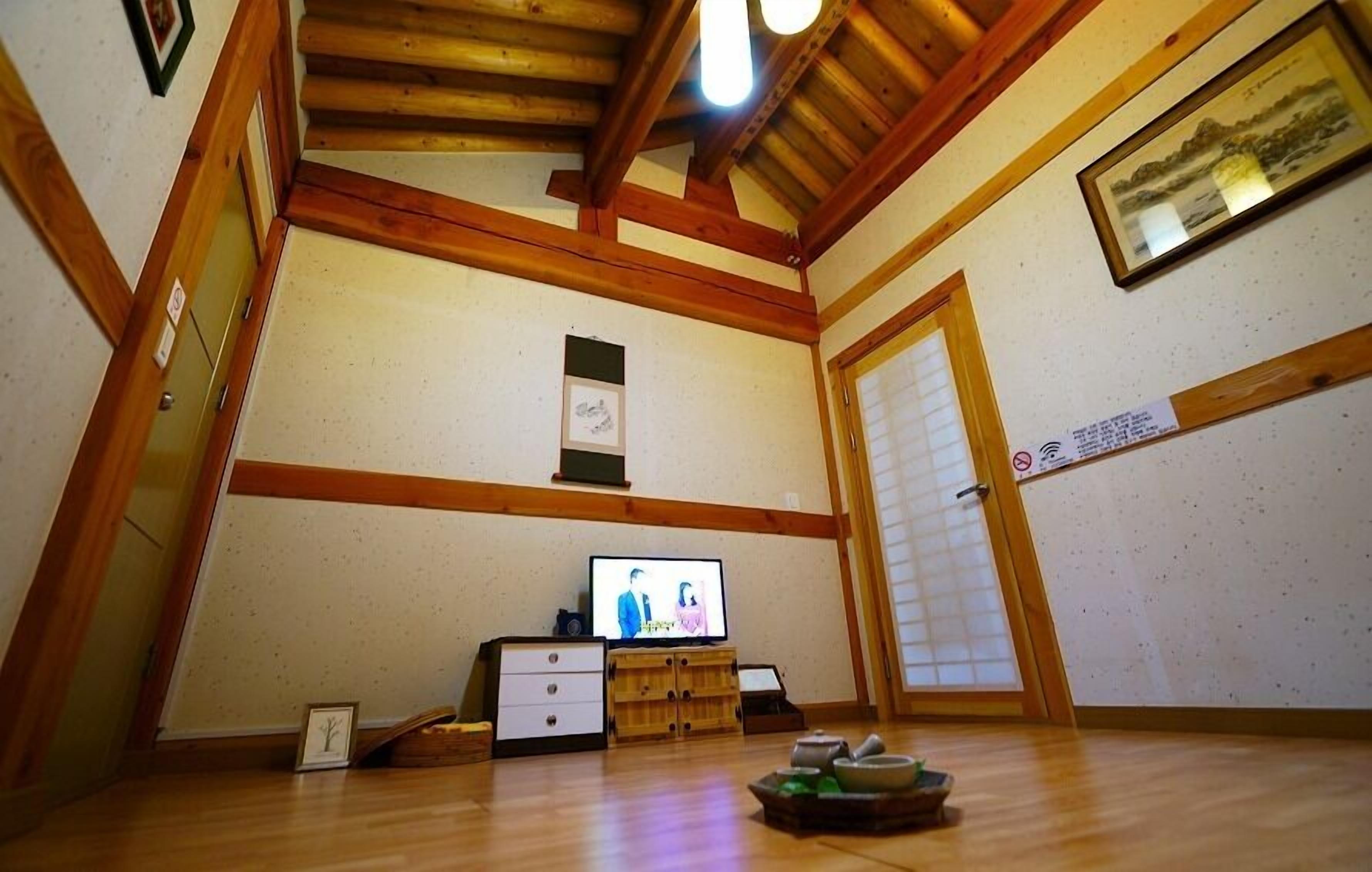 A room with wooden beams, a television, a small cabinet, and a traditional Japanese sliding door.