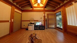 A traditional Japanese room with wooden beams, tatami flooring, a television, and a futon bed.