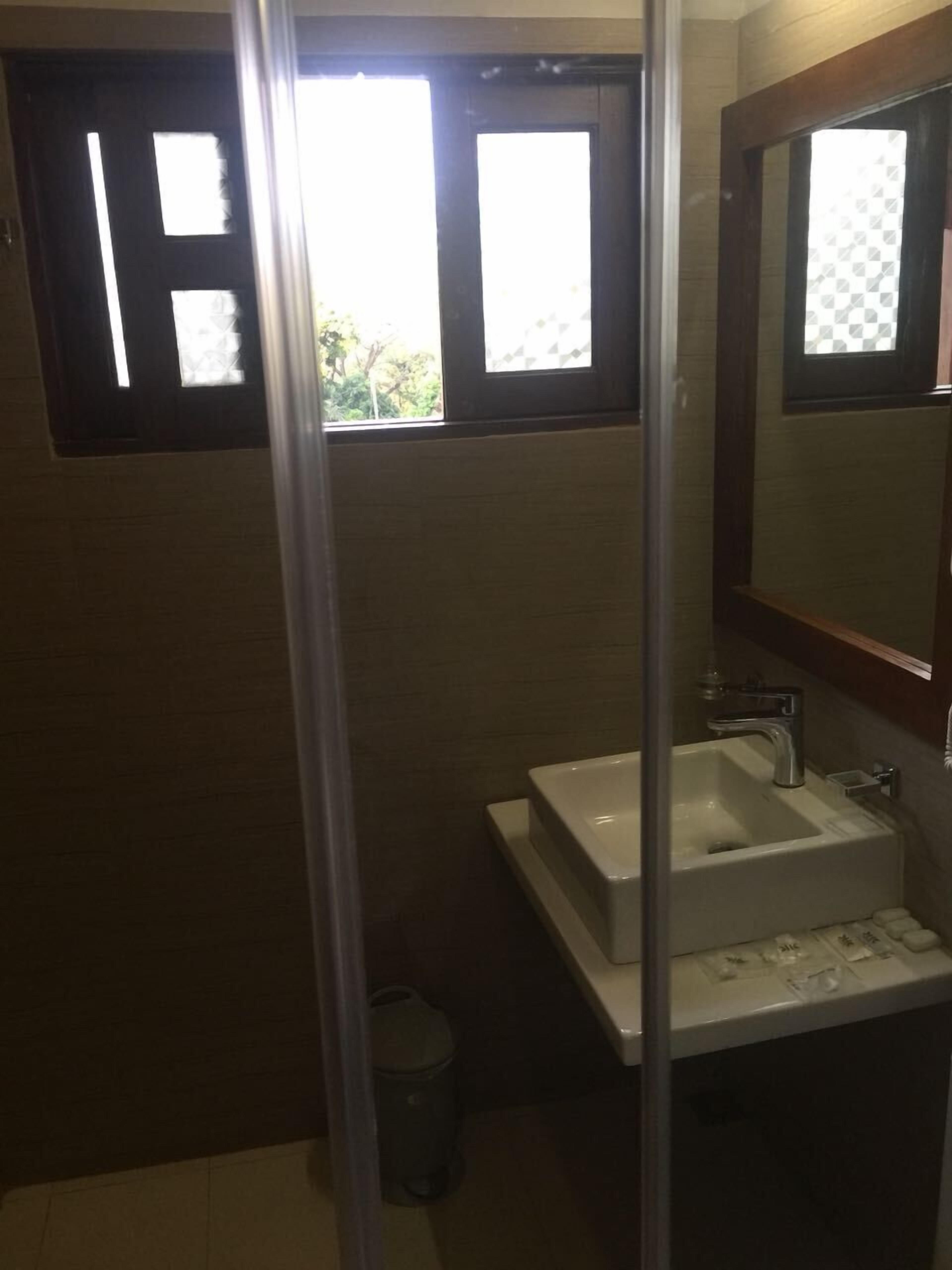 A bathroom with a white sink, a mirror, and a window with blinds.