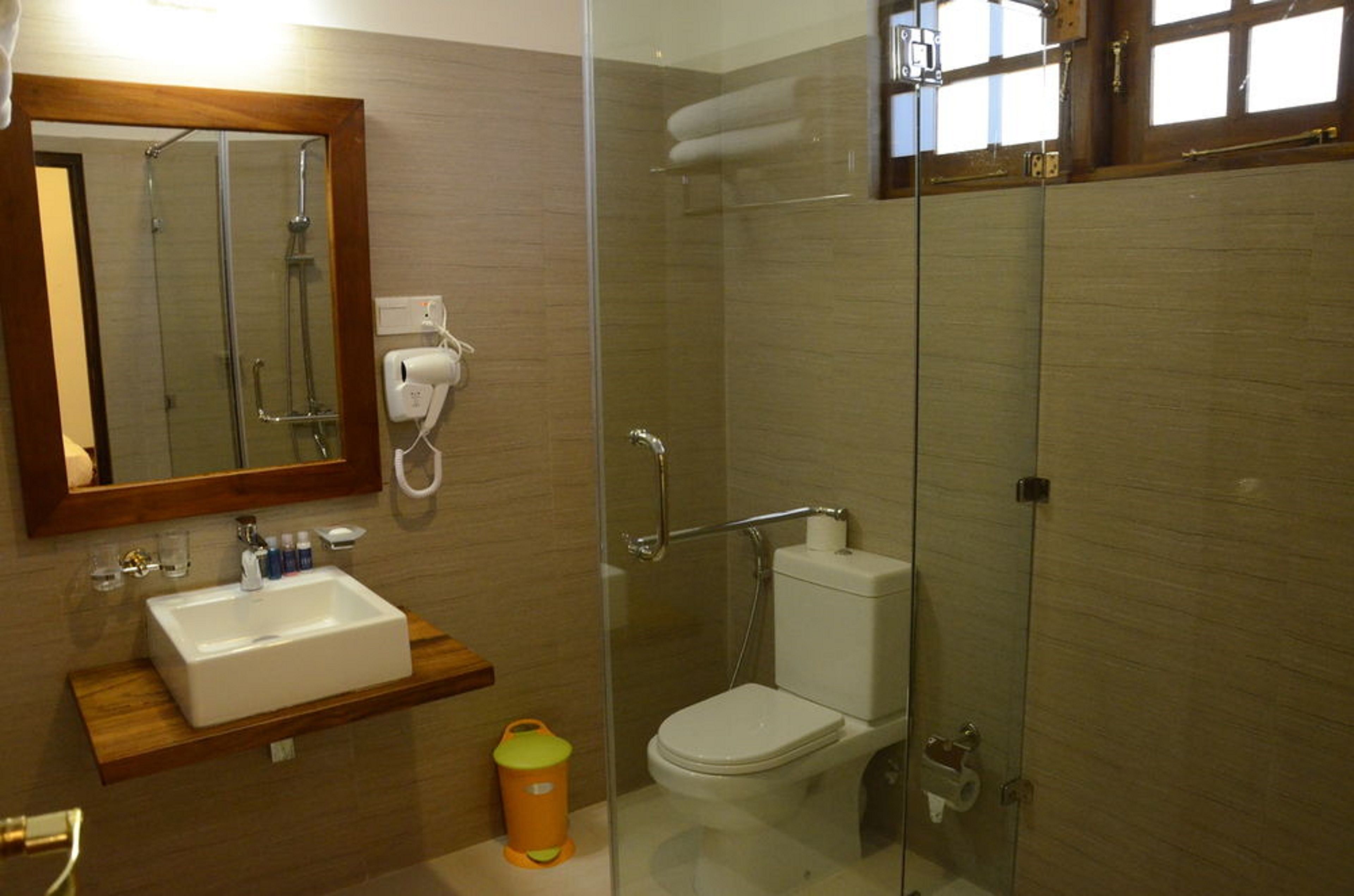 A modern bathroom with a glass-enclosed shower, a white sink, and a toilet.
