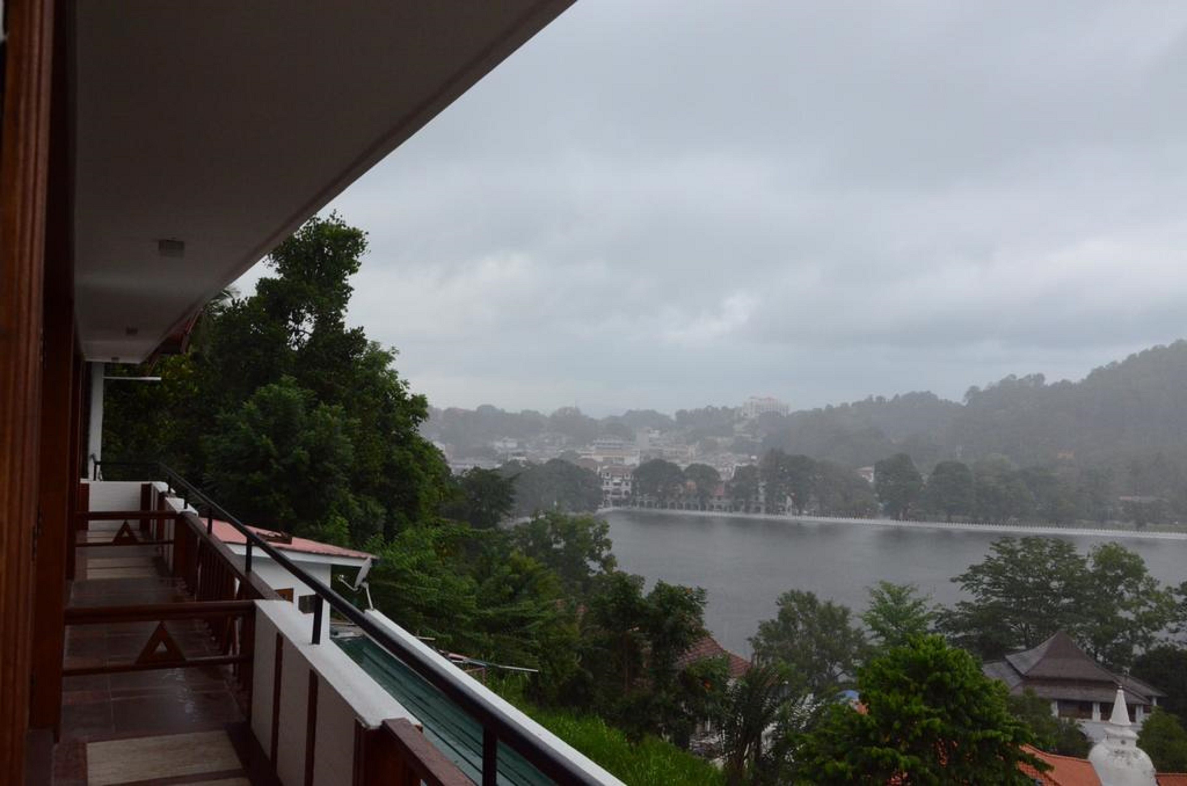 A balcony with a view of a lake and surrounding hills.