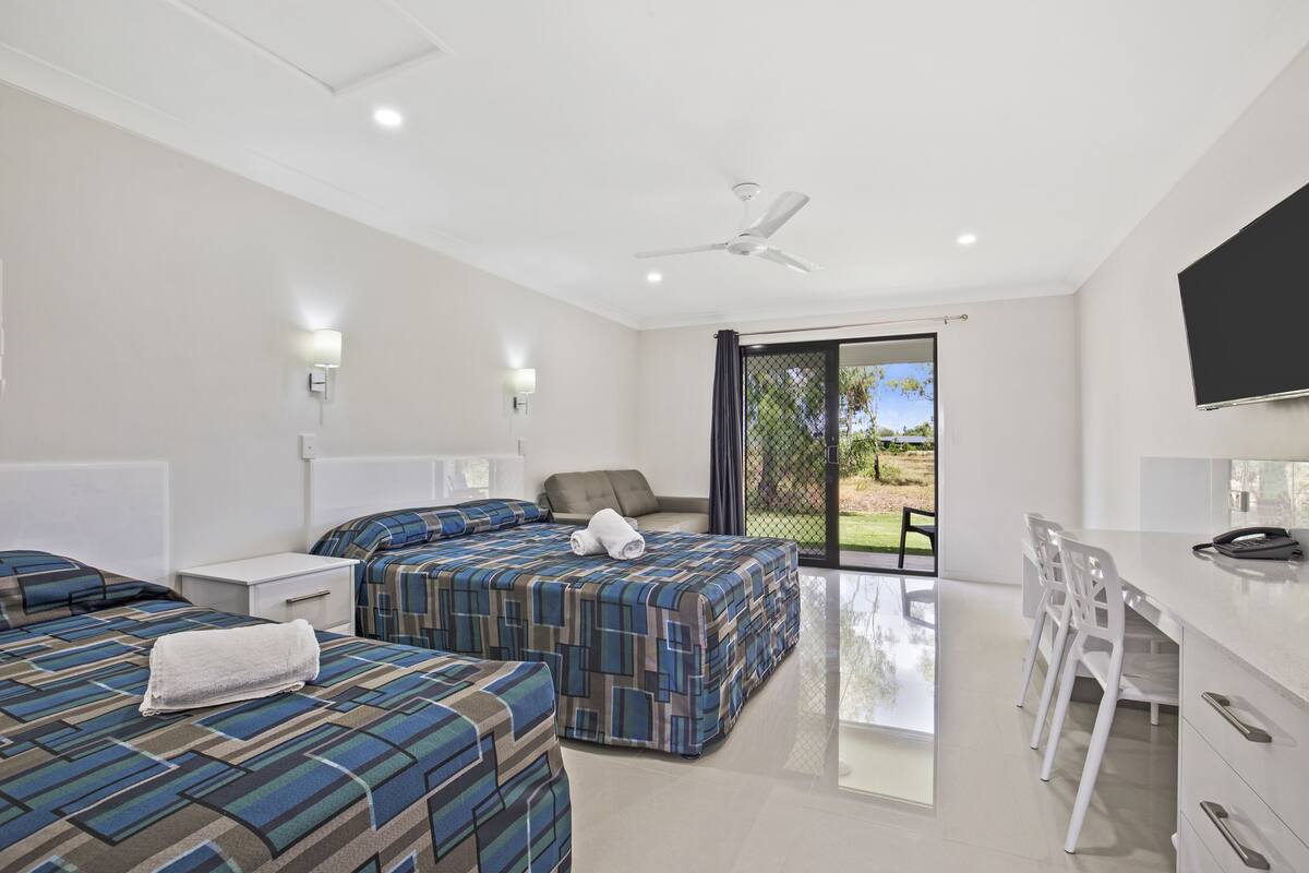 A modern hotel room with two beds, a desk, and a TV.