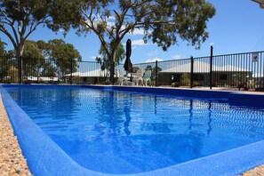 Una piscina al aire libre, sillones reclinables de piscina