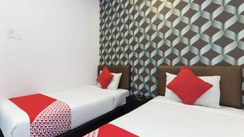 Una habitación de hotel con dos camas, cada una con una colcha de cuadros rojos y blancos. Las paredes tienen un papel tapiz con motivos geométricos.