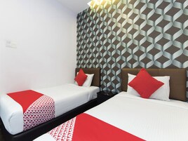 Una habitación de hotel con dos camas, cada una con una colcha de cuadros rojos y blancos. Las paredes tienen un papel tapiz con motivos geométricos.