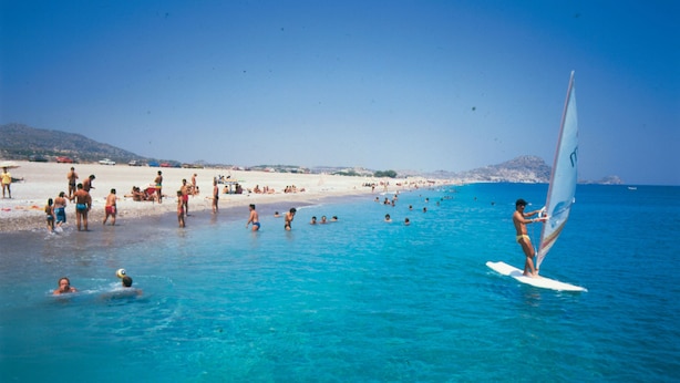 A beach with people swimming and one person windsurfing. - Oasis Hotel Bungalows Rodos  (Rhodes)